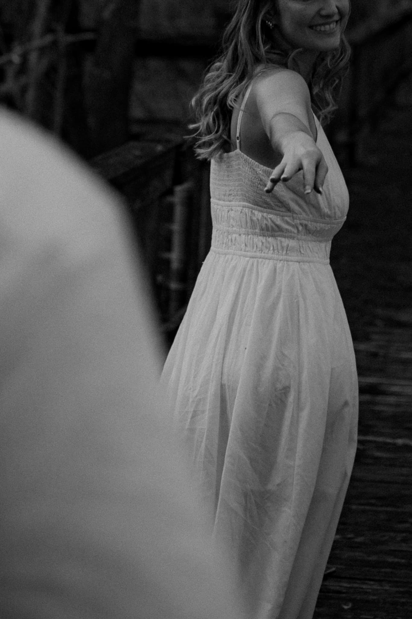 Couple reaching toward one another in a candid black-and-white portrait